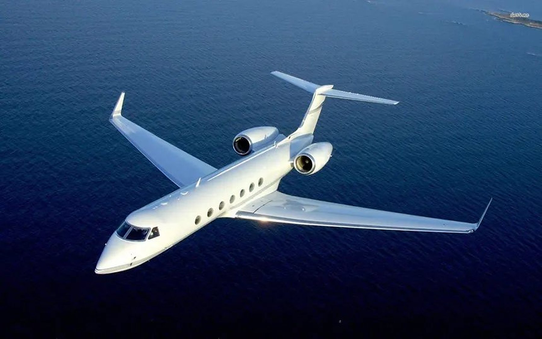 White private jet flying over deep blue sea