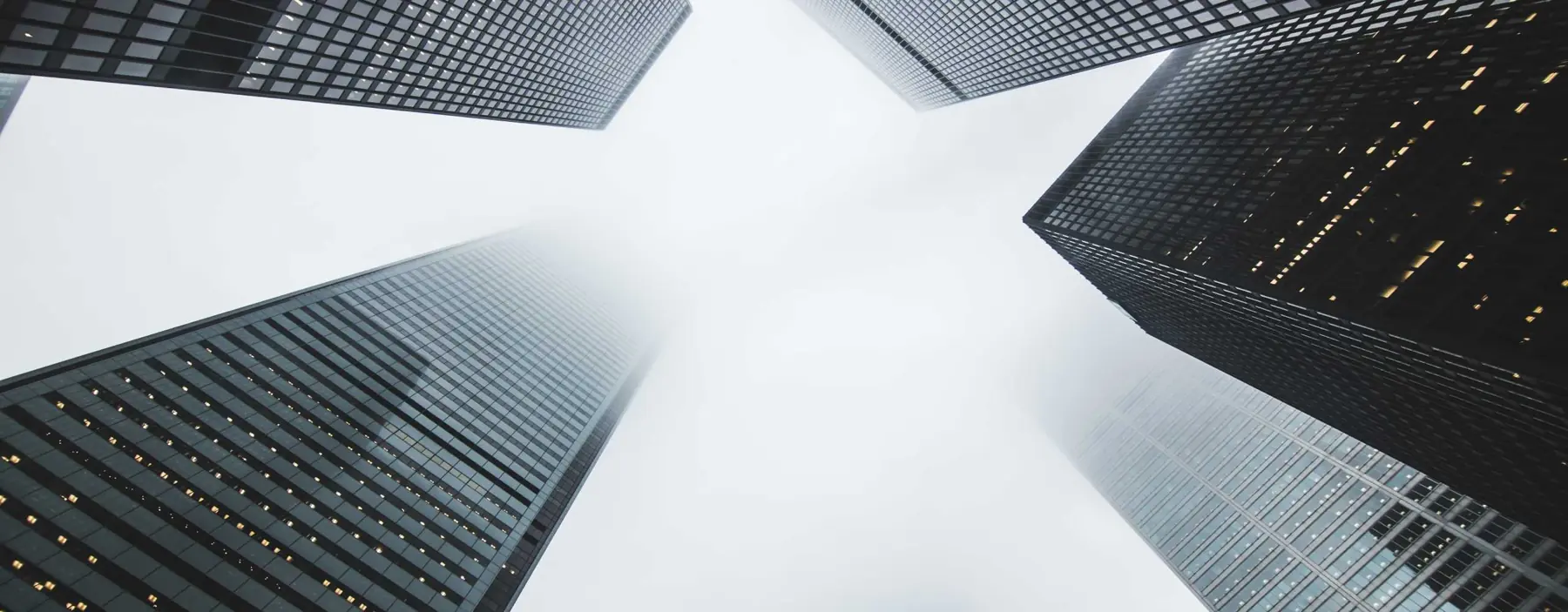 Glass office towers seen from street level rising into the sky