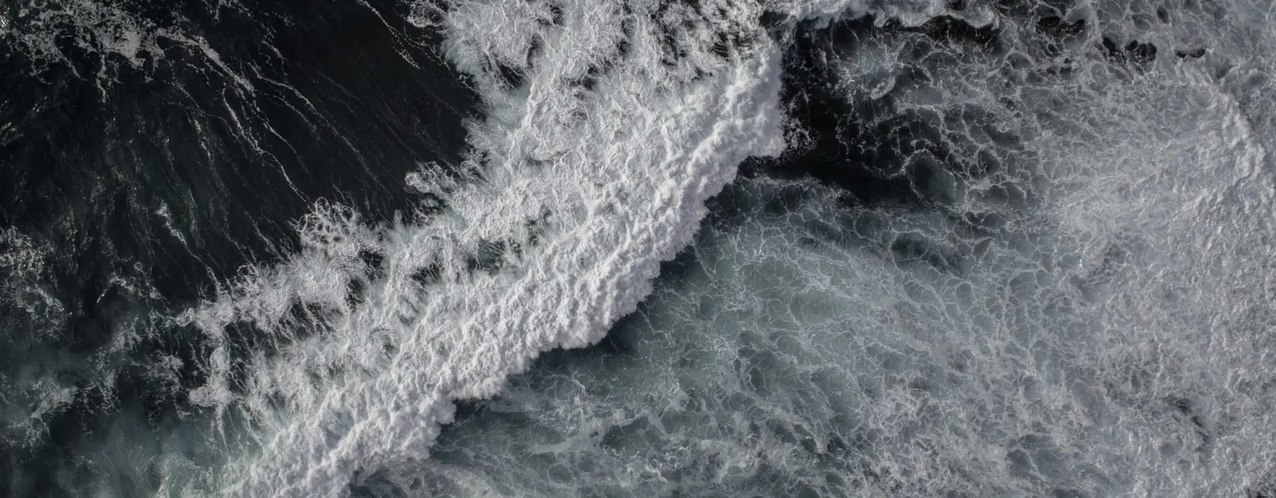 Aerial view of dark ocean waves breaking